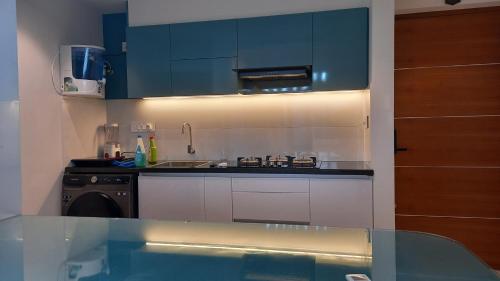 a kitchen with blue cabinets and a sink and a stove at 'Savitham' City View flat in Trivandrum in Trivandrum