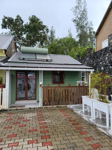 a green house with a porch and two white benches at Le Cyprès in Cilaos