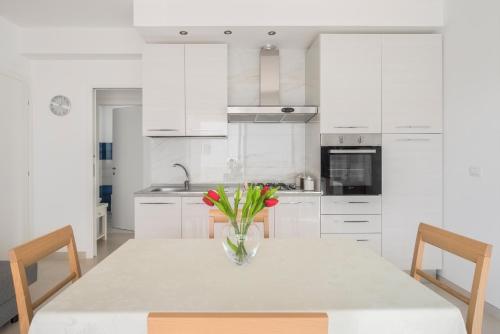 a white kitchen with a vase of flowers on a table at DolceVitaSuites - Modern 3 Bdr Villa in S. Lorenzo in San Lorenzo