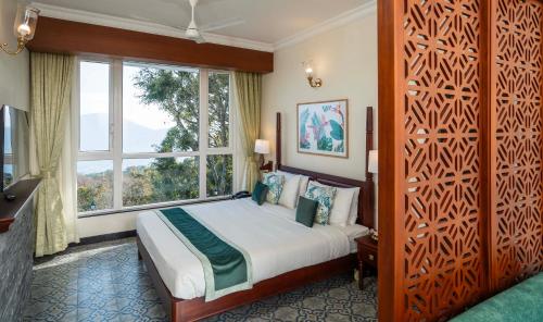 a bedroom with a bed and a large window at Fort Munnar in Chinnakanal