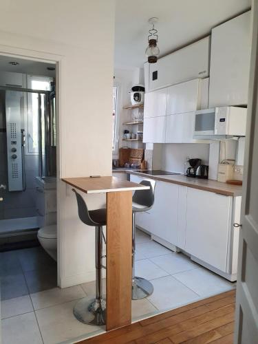 une cuisine avec des armoires blanches et un comptoir en bois dans l'établissement Chambre privée dans magnifique appartement calme, à Paris