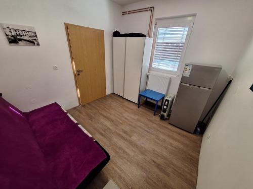 a small room with a purple couch and a refrigerator at Apartment GREEN&URBAN in Celje