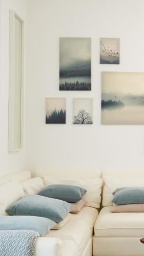 Canal view 3 bedroom holiday home with balcony في أبوظبي: أريكة بيضاء في غرفة معيشة مع صور على الحائط
