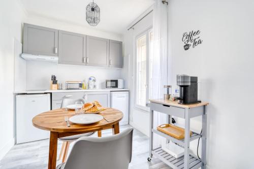 cocina con armarios blancos y mesa de madera en Magnifique Appart Cosy Rénové Gare 2 pers, en Gagny