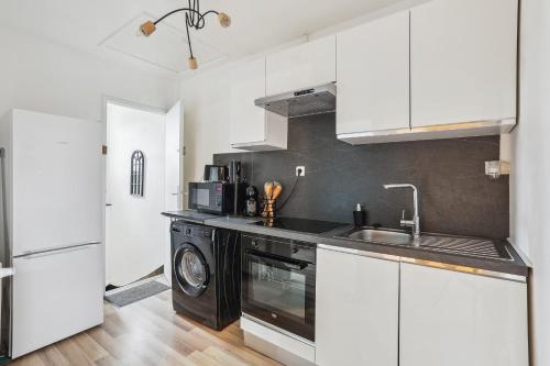 une cuisine avec des armoires blanches, un évier et un lave-vaisselle dans l'établissement Magnifique Appart centre ville rénové 2 pers, au Mans