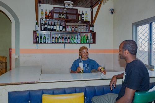 Ein Mann und eine Frau sitzen in einer Bar in der Unterkunft COMPLEXE GROUPE NJAYOU SARL-U (CGN HOTEL) in Mapara