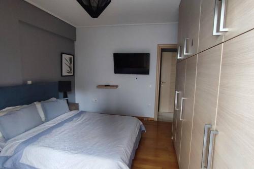 a bedroom with a bed and a flat screen tv at Seaside Haven - Alimos in Athens