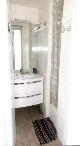 une salle de bain blanche avec un lavabo et un miroir dans l'établissement Studio cabine Grau D Agde résidence avec piscine, au Grau-dʼAgde