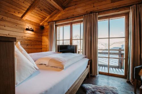 a bedroom with a bed and a large window at Chaletdorf BERGHERZ in Sankt Johann im Pongau