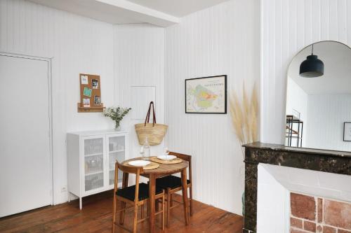 a living room with a table and a fireplace at Le Studio de la Bastide - Classé 2 étoiles - Libourne in Libourne