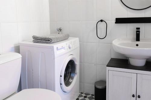 a white bathroom with a washing machine and a sink at Le Studio de la Bastide - Classé 2 étoiles - Libourne in Libourne