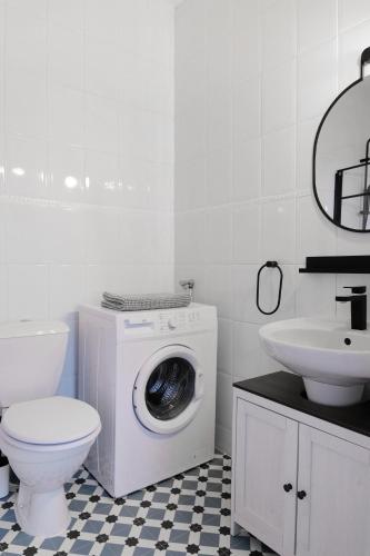 a white bathroom with a washing machine and a sink at Le Studio de la Bastide - Classé 2 étoiles - Libourne in Libourne