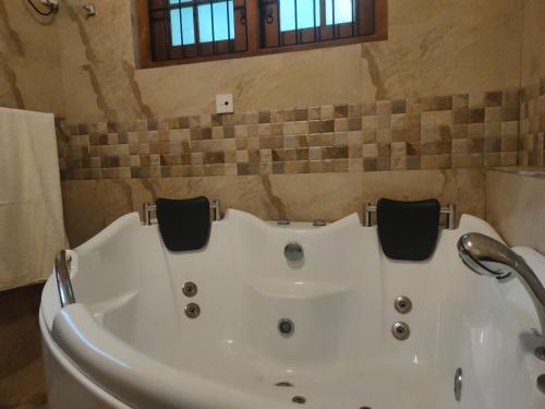 a white bath tub in a bathroom with a window at Heaven Palace in Kandy