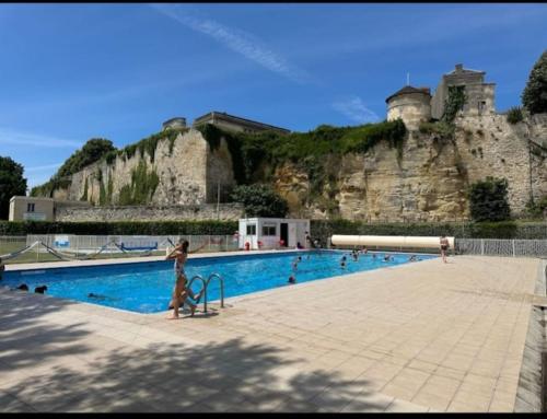 une grande piscine avec un château en arrière-plan dans l'établissement Maison Girondine 4 personnes, à Saint-Seurin-de-Bourg