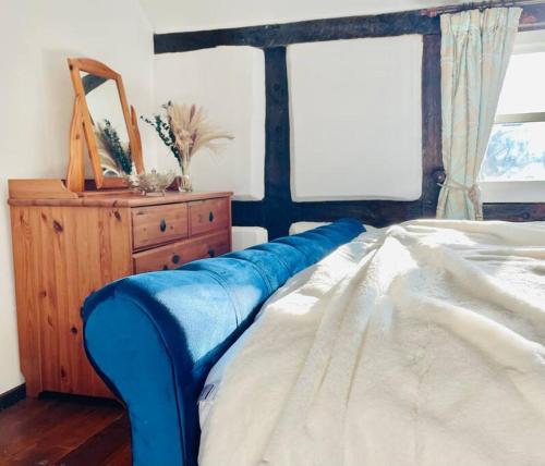 a bedroom with a bed with a blue blanket on it at Rolling Hills and Woodland Views!-2 bed cottage with dog walking trails and local pub on your doorstep! Popular walking trails nearby-Malvern Hills and the Brockhampton Estate- Peaceful village on the border of Hereford and Worcester in Worcester