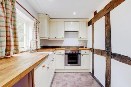 a kitchen with white cabinets and a wooden counter top at Log Burner and Beamed Ceilings-2 Bed Cottage Crumpelbury and Whitbourne Hall less than a 4 minute drive Dog walking trails and local pub within walking distance and a 30 minute drive to the Malvern Hills in Worcester