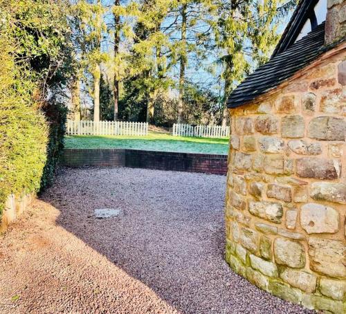 a brick wall next to a yard with a fence at Rolling Hills and Woodland Views!-2 bed cottage with dog walking trails and local pub on your doorstep! Popular walking trails nearby-Malvern Hills and the Brockhampton Estate- Peaceful village on the border of Hereford and Worcester in Worcester