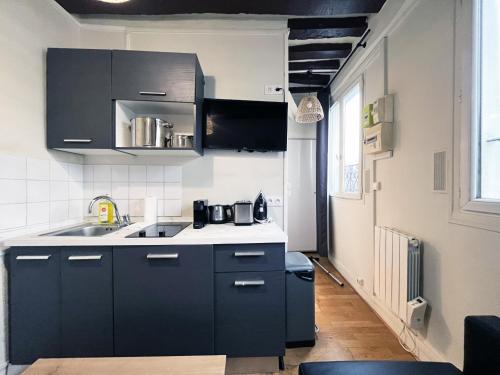 - une cuisine avec des placards noirs et un évier dans l'établissement 164 - Charming Studio in Center of Paris, à Paris