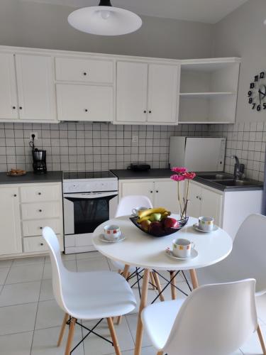 a kitchen with a white table and white chairs at Nini's Houses in Nydri
