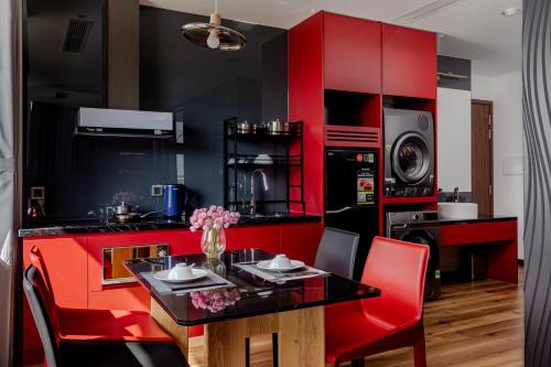 a red kitchen with a table and red chairs at Taiyo Hotel & Apartment in Da Nang