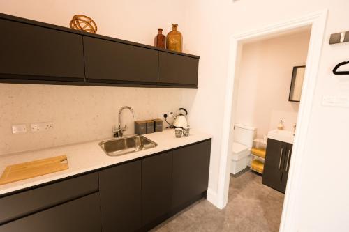 a kitchen with black cabinets and a sink at The Old Workshop in Higher Burwardsley