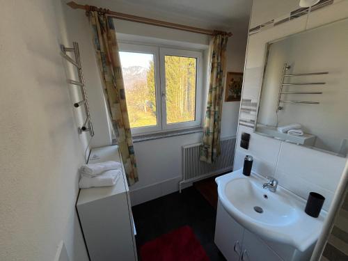 La salle de bains blanche est pourvue d'un lavabo et d'une fenêtre. dans l'établissement Ferienwohnung am Stambach, à Bad Goisern