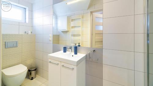 a white bathroom with a toilet and a sink at Apartamenty Good Time - Kora Cieplice in Jelenia Góra