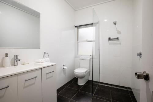 a white bathroom with a toilet and a glass shower at McCaffrey's Estate in Pokolbin