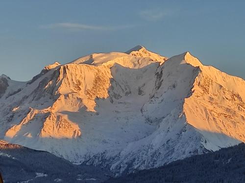 a snow covered mountain with the sun shining on it at Chambre Sallanches in Sallanches
