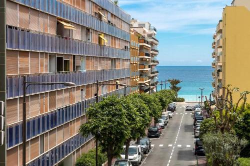 un immeuble avec des voitures garées dans une rue à côté de l'océan dans l'établissement Studio Monaco, à Roquebrune-Cap-Martin