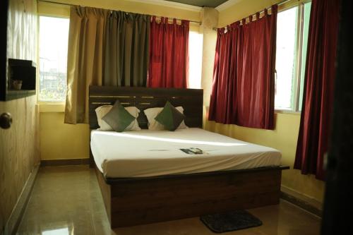 a bedroom with a large bed with red curtains at HOTEL AIRPORT HEAVEN in kolkata