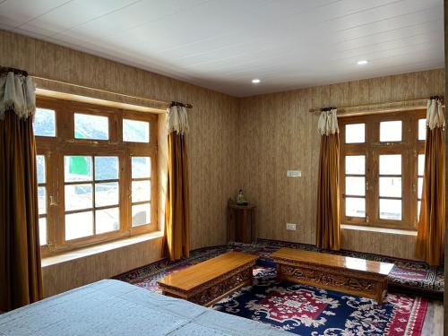 a bedroom with a bed and two windows at SNOWFLAKE Homestay in Gondla