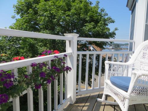 a white porch with a chair and flowers at Atlantic Ark Inn in Boothbay Harbor
