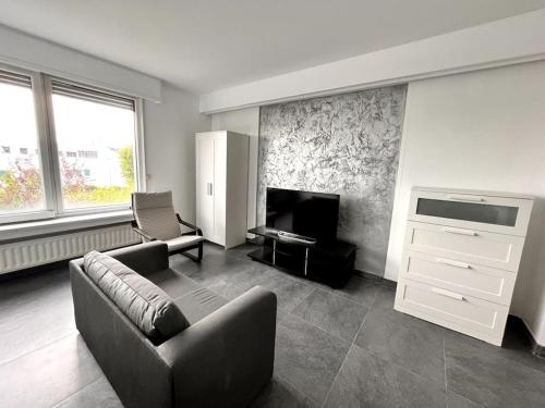 a living room with a couch and a television at Stylish Fully Equipped Studio Close to Centre in Luxembourg