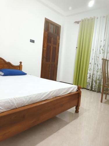 a bedroom with a bed and a green curtain at White's vila in Matara