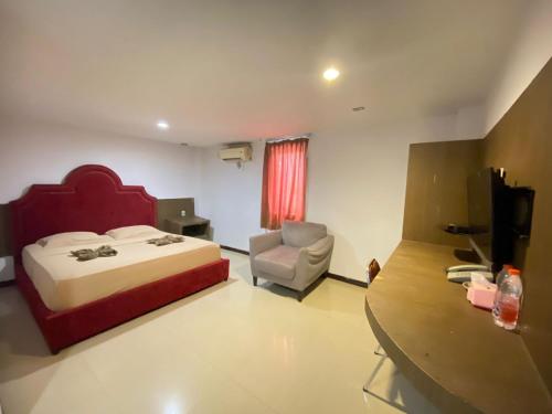 a bedroom with a bed and a chair and a desk at New Z Suites in Sunggal
