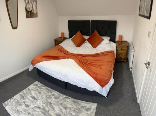 a bedroom with a large bed with an orange blanket at No.46, comfortable 2 bedroom property in Rothes