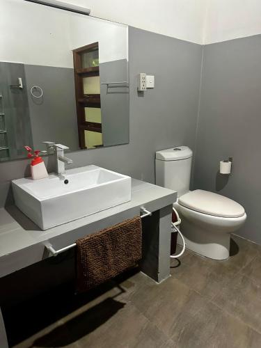a bathroom with a white sink and a toilet at Sat Nam Village Hotel in Sigiriya