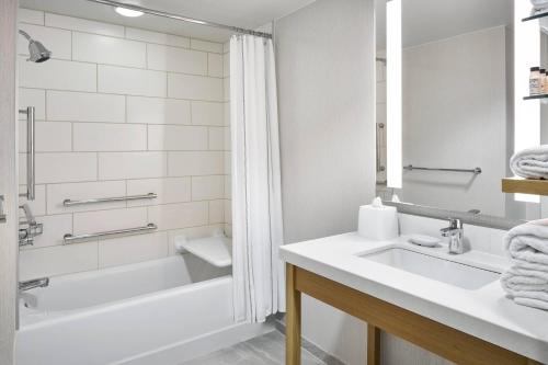 a bathroom with a sink and a bath tub at Delta Hotels by Marriott Norfolk Airport in Norfolk