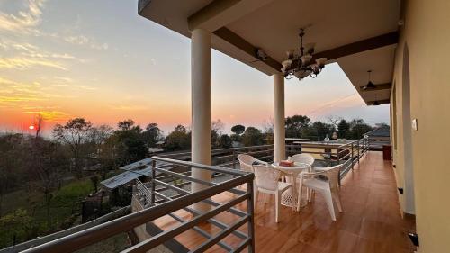a balcony with a table and chairs and a sunset at The Lumi in Bīr