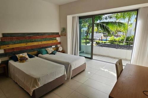 a bedroom with two beds and a balcony at Villa golf de Montchoisy in Mont Choisy