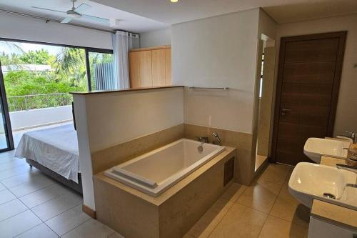 a bathroom with a tub and a sink and a bed at Villa golf de Montchoisy in Mont Choisy