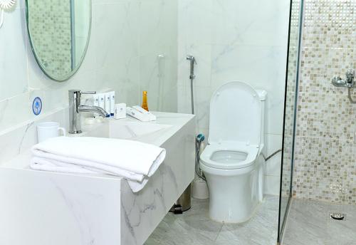 a white bathroom with a toilet and a shower at Art Suite in Riyadh