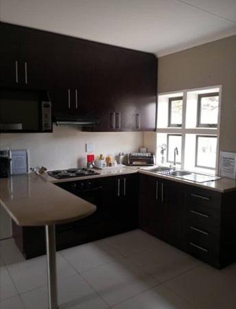 a kitchen with black cabinets and a sink and a stove at Noble Luminous Accommodation and Tours in Rehoboth