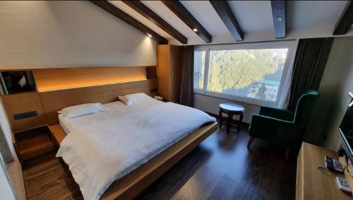 a bedroom with a bed and a chair and a window at Deep Hotel in Mussoorie