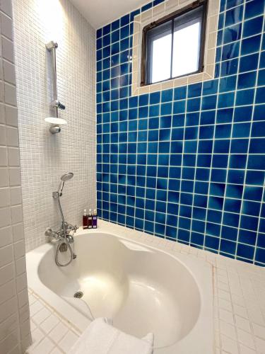 a blue tiled bathroom with a tub and a window at At Niman conceptual Home chiangmai in Chiang Mai