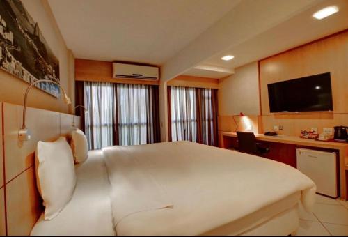 um quarto com uma grande cama branca e uma secretária em Quádruplo Autônomo Quality no Rio de Janeiro