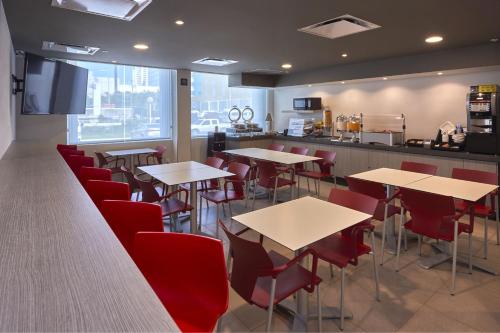 a restaurant with tables and red chairs and a counter at City Express Junior by Marriott Villahermosa in Villahermosa