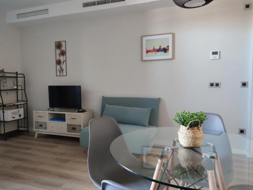 a living room with a glass table and a tv at Apartamento Servet, parking gratuito, a 5 minutos de Sevilla in Bormujos