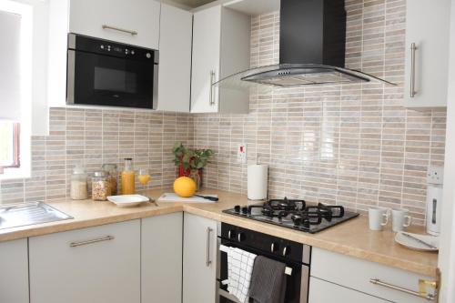 cocina con armarios blancos y fogones en Greenfield House, en Norwich